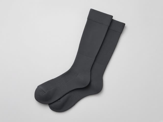 Paire de chaussettes de compression de sport gris anthracite montant sous le genou, posées à plat sur un fond gris clair